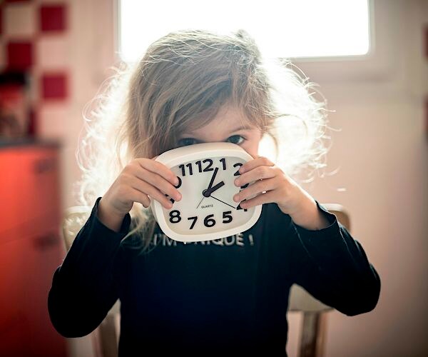 a little girls holds up an old fashioned alarm clock in her bedroom