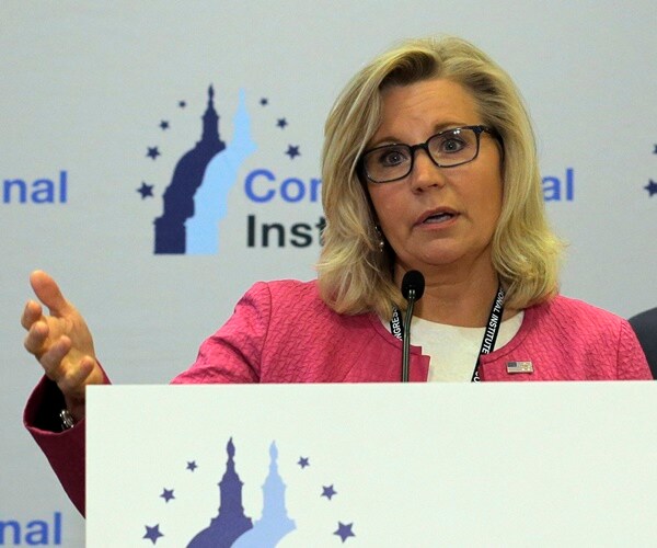 liz cheney stands at a congressional institute podium