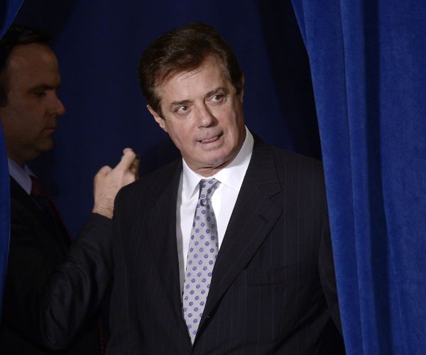 paul manafort peers from behind a curtain, looking to his left around it