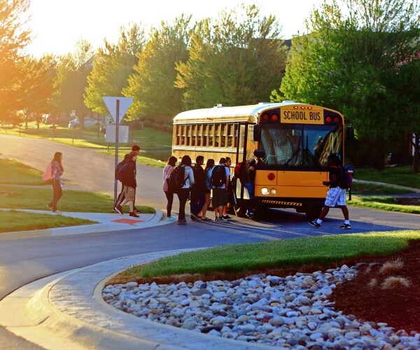 children in a line getting on school bus in the morning