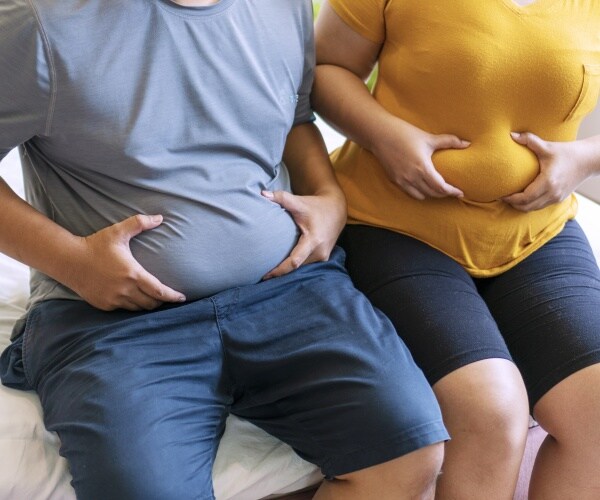 man and woman holding their belly fat