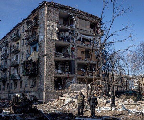 Police and military personnel stand in front of a residential apartment complex