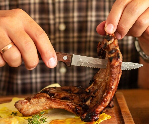 a man cutting a piece of steak with a sharp knife