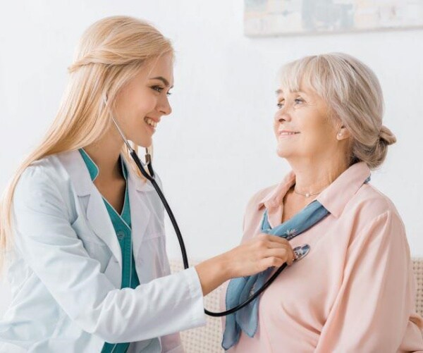 female doctor checking heartbeat of older woman patient