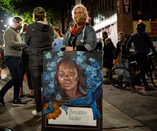 a demonstrator holds a painting of Breonna Taylor