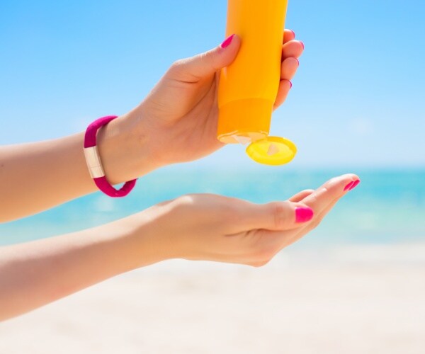 woman squeezing sunscreen into hand