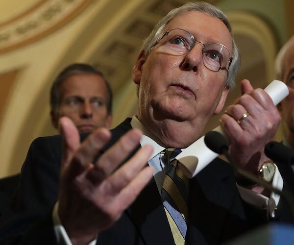 mitch mcconnell holds a scroll of paper and gestures during a capitol hill news conference